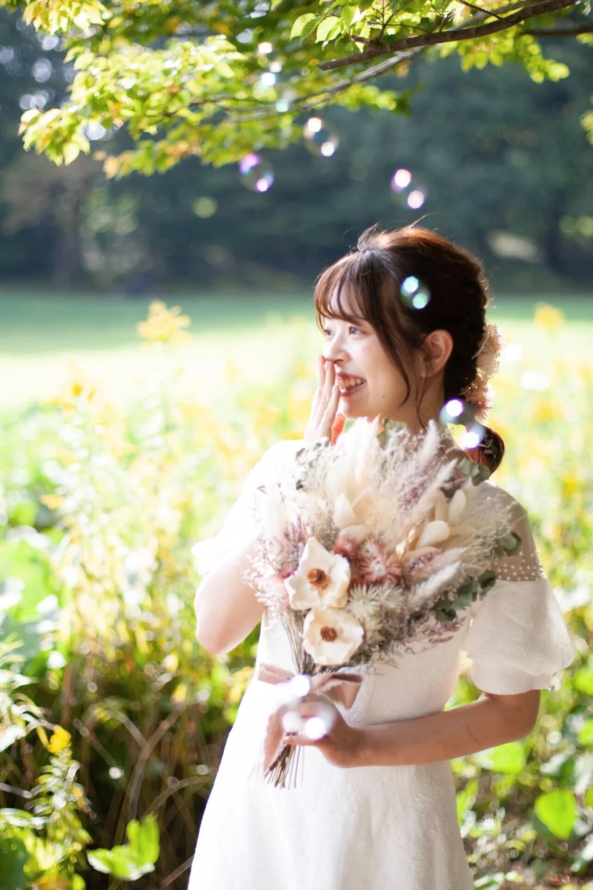 小林伽奈さん撮影作品。緑の中で花束を持つ女性を柔らかな光で写したポートレート